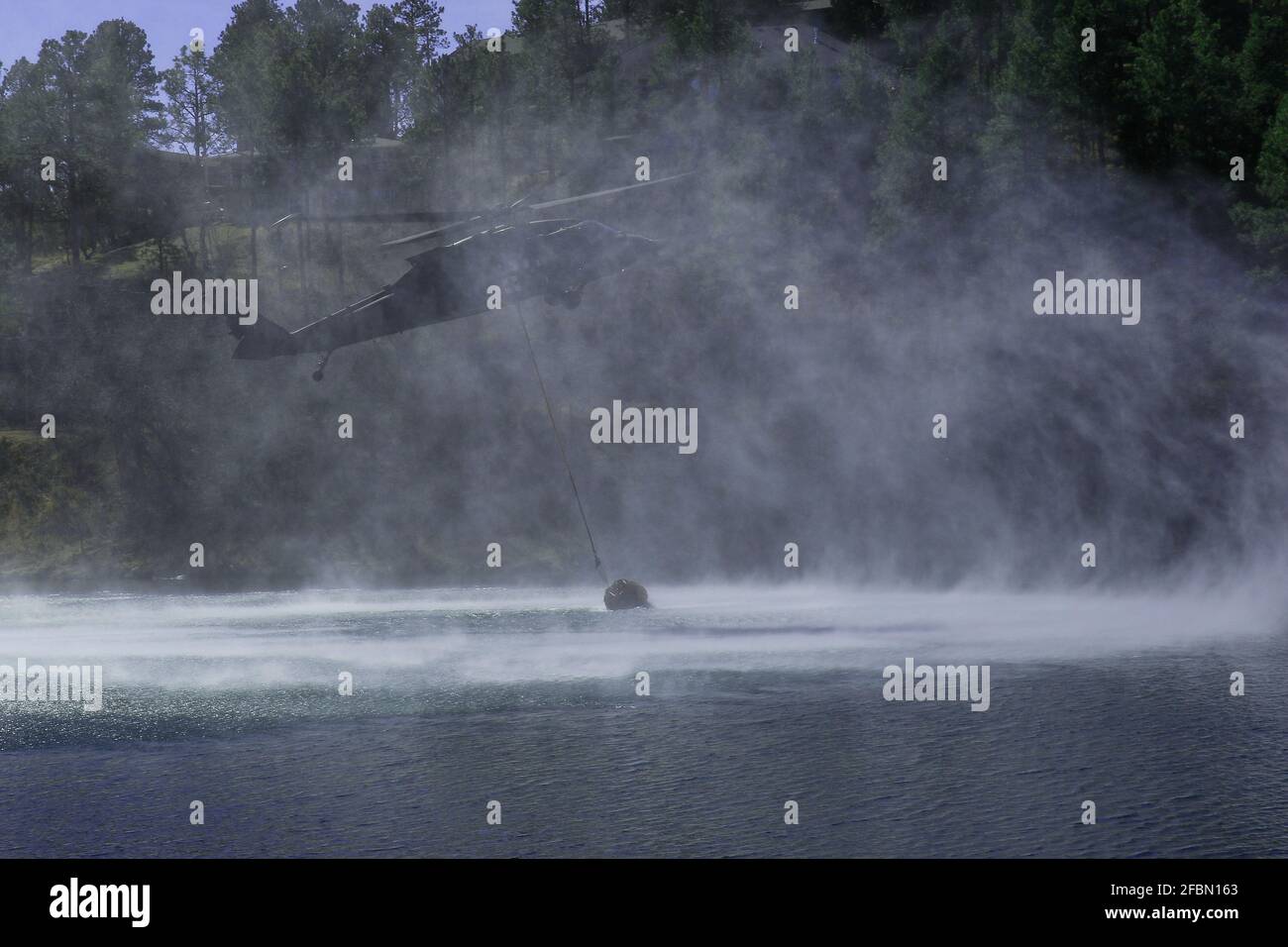Elicottero che riceve acqua da Canyon Lake South Dakota per assistere nel controllo di un fuoco selvaggio Foto Stock