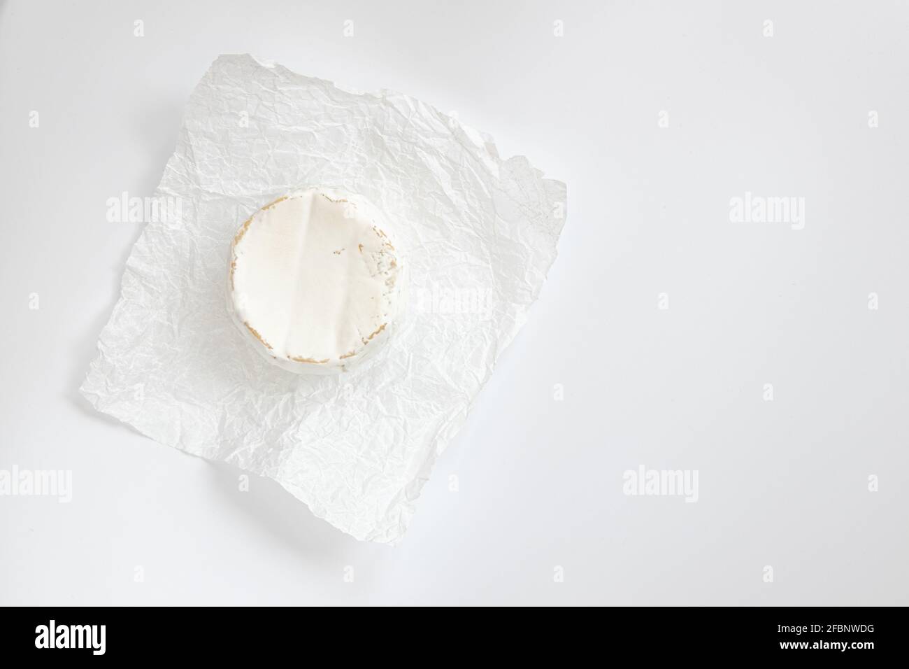 formaggio camembert o brie su sfondo bianco, formaggio su carta pergamena bianca, testa di gustoso camembert o brie formaggio, formaggio francese, vista dall'alto Foto Stock