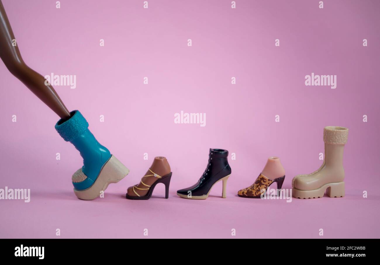 Scarpe da bambola con una bambola che cammina su un morbido sfondo rosa. Concetto minimo di shopping e moda. Con spazio per la copia. Foto Stock