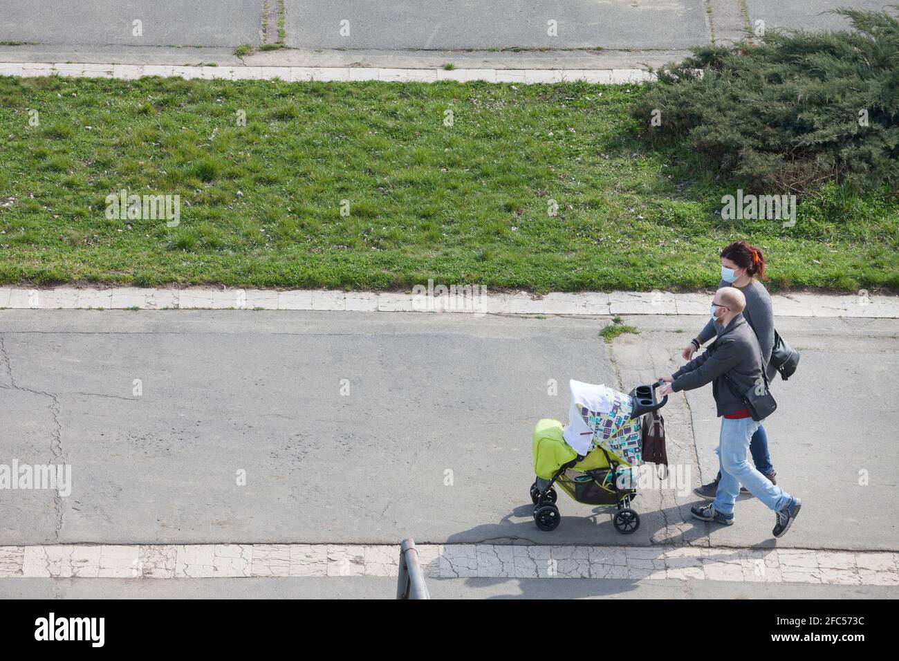 BELGRADO, SERBIA - 27 MARZO 2021: Famiglia europea, padre e madre, e il loro bambino, in passeggino, a piedi indossare maschera di protezione equipaggiamento Foto Stock