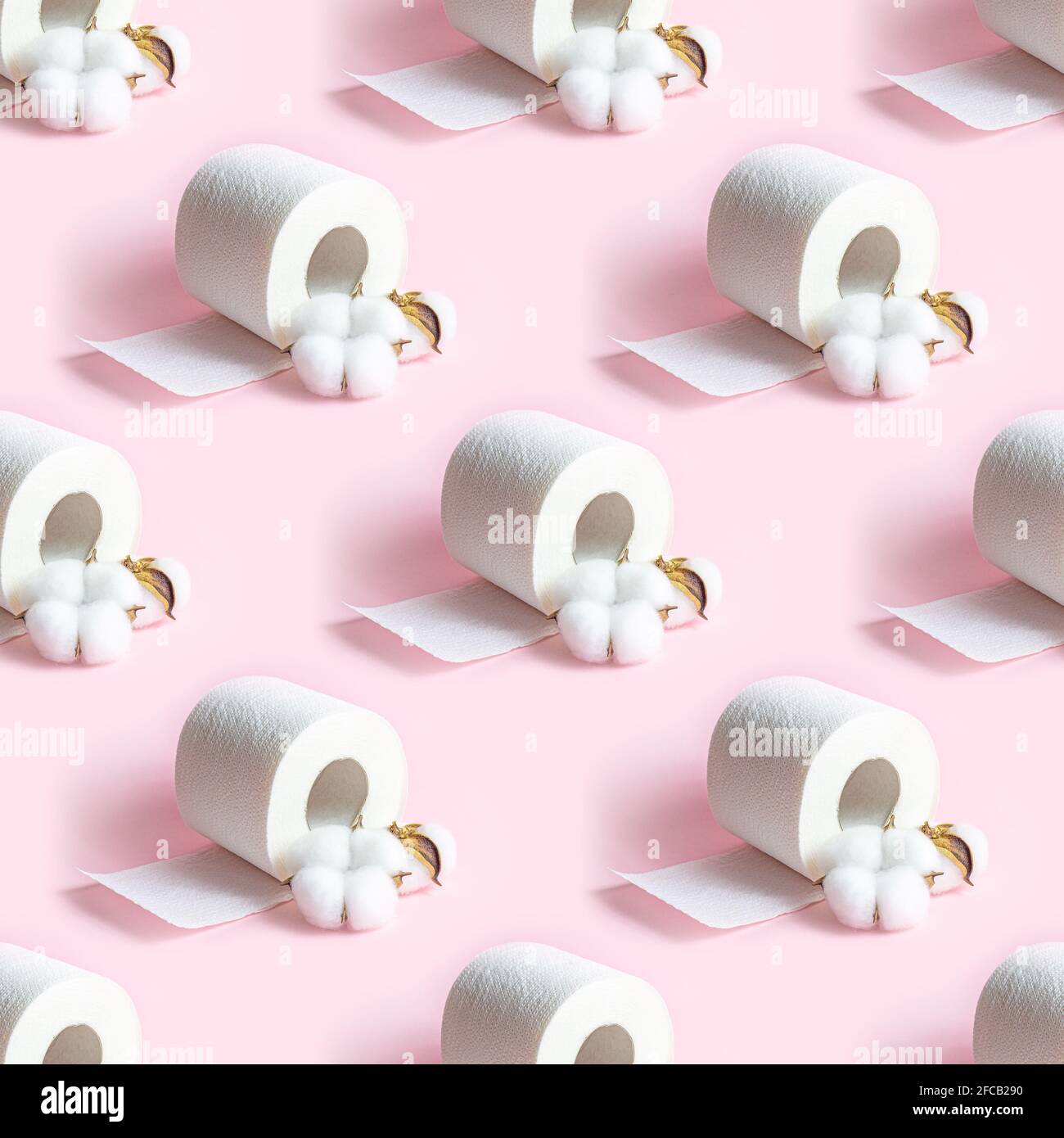 Il rotolo di carta igienica bianca ripete un motivo continuo su sfondo rosa chiaro. Foto Stock