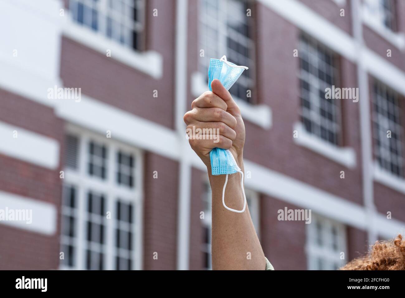 Primo piano della mano di un uomo di razza mista che tiene un volto maschera Foto Stock