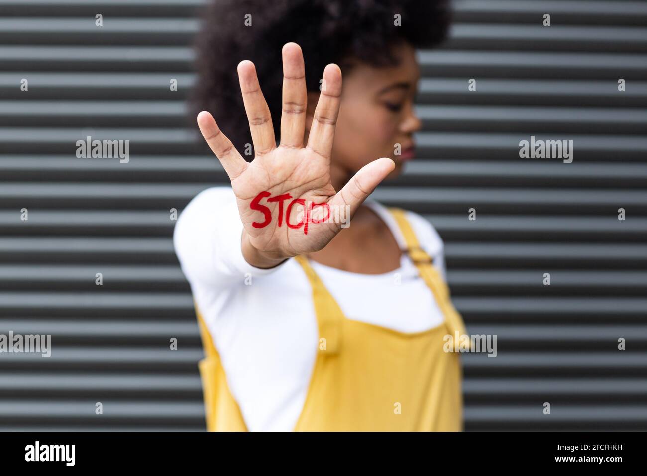 Ritratto di donna di razza mista che fa gesto di stop con la mano coperto per iscritto Foto Stock