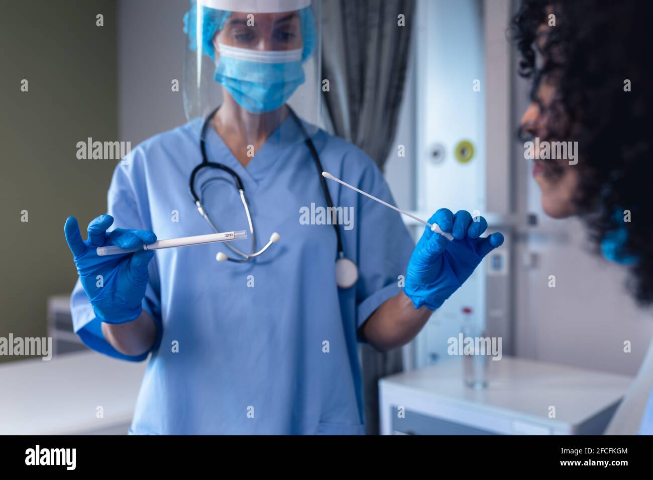 Paziente femminile afro-americana testato con tampone di prova da femmina medico in maschera facciale Foto Stock