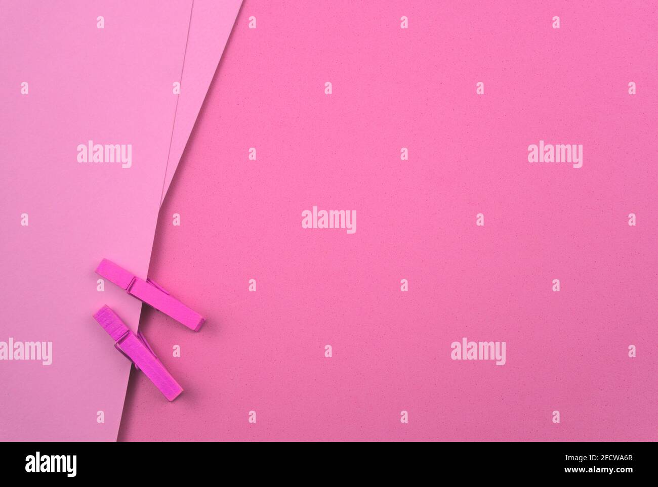 Carta bianca color pastello rosa con fermagli in legno, pioli. Astratto sfondo minimo di trama della carta. Spazio libero per il testo, l'immagine o il disegno. Foto Stock