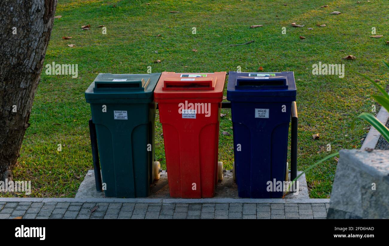 Contenitori colorati per rifiuti allineati nel parco del forte di Galle, verdi per materiale organico e il contenitore arancione per polietilene di plastica, e bidone blu per rifiuti di carta Foto Stock