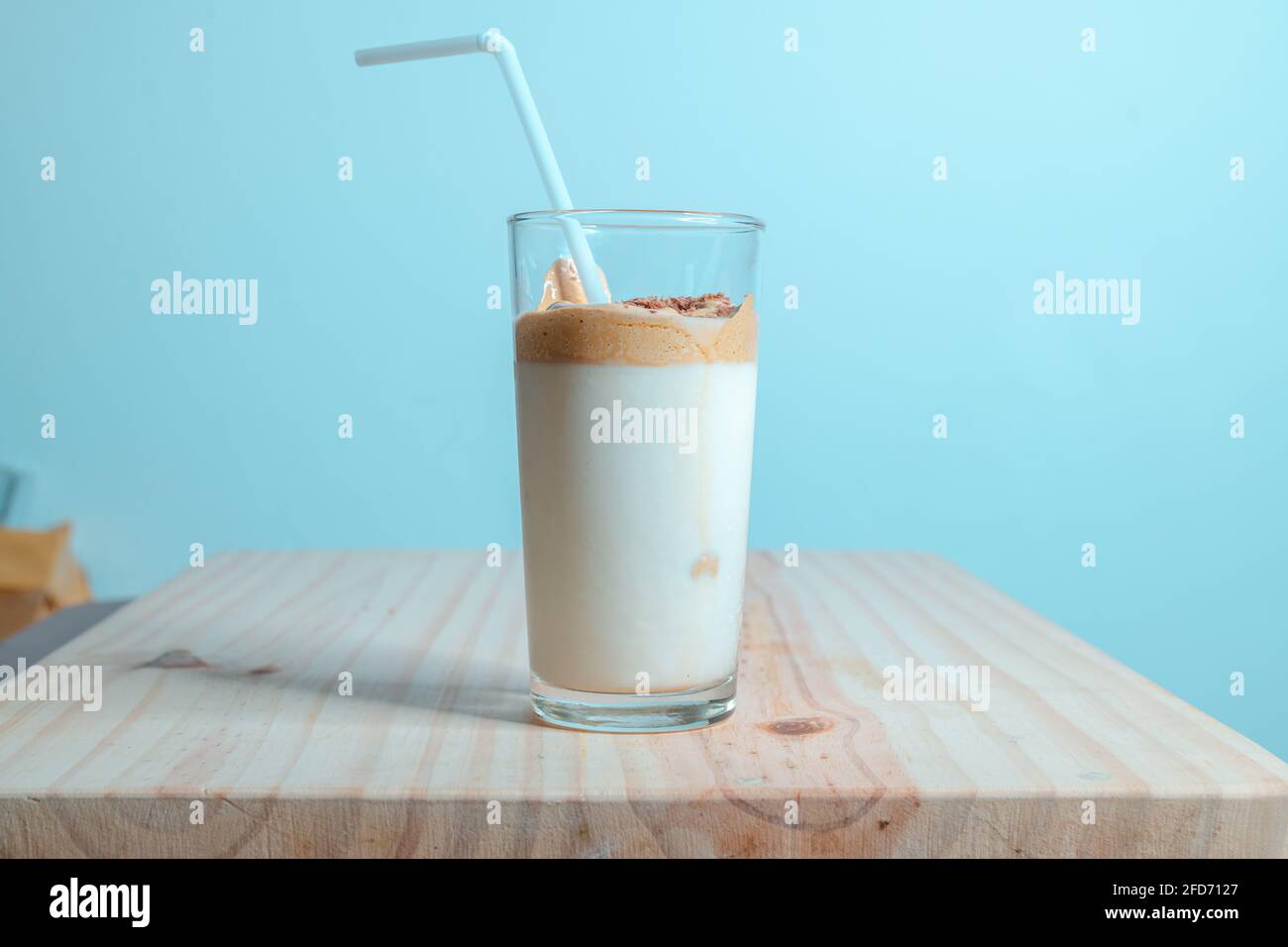 Bicchiere da caffè Dalgona fatto in casa su un tavolo in legno testurizzato. Caffè istantaneo con latte fresco, per preparare la deliziosa bevanda coreana. Alla moda Foto Stock