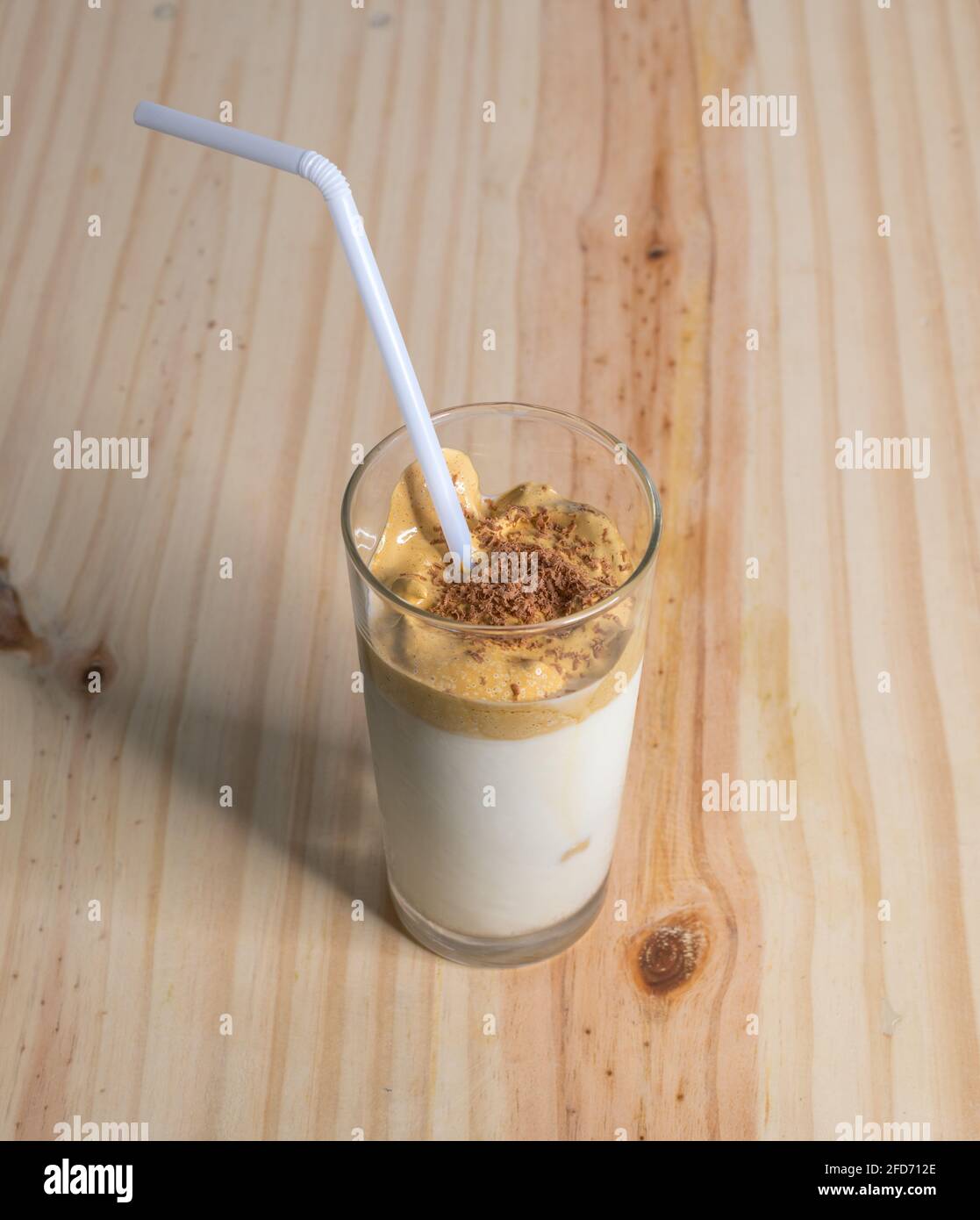 Bicchiere da caffè Dalgona fatto in casa su un tavolo in legno testurizzato. Caffè istantaneo con latte fresco, per preparare la deliziosa bevanda coreana. Alla moda Foto Stock