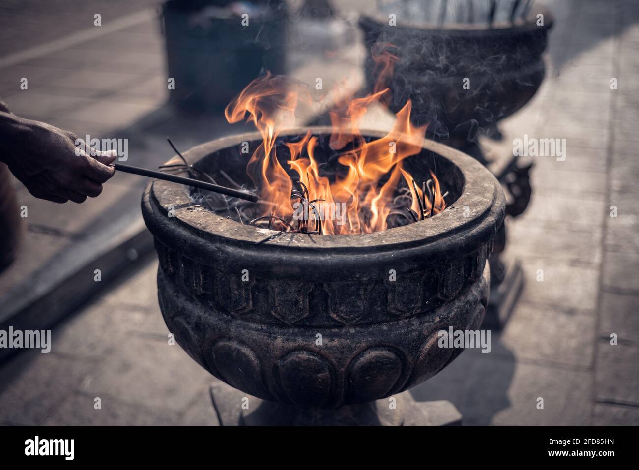 Bruciando bastoni di incenso in pentola di pietra Jaya Sri Maha Bodhi Anuradhapura, una vecchia mano con bastoni di incenso, pellegrino che illumina i suoi bastoni dal fuoco, p. Foto Stock