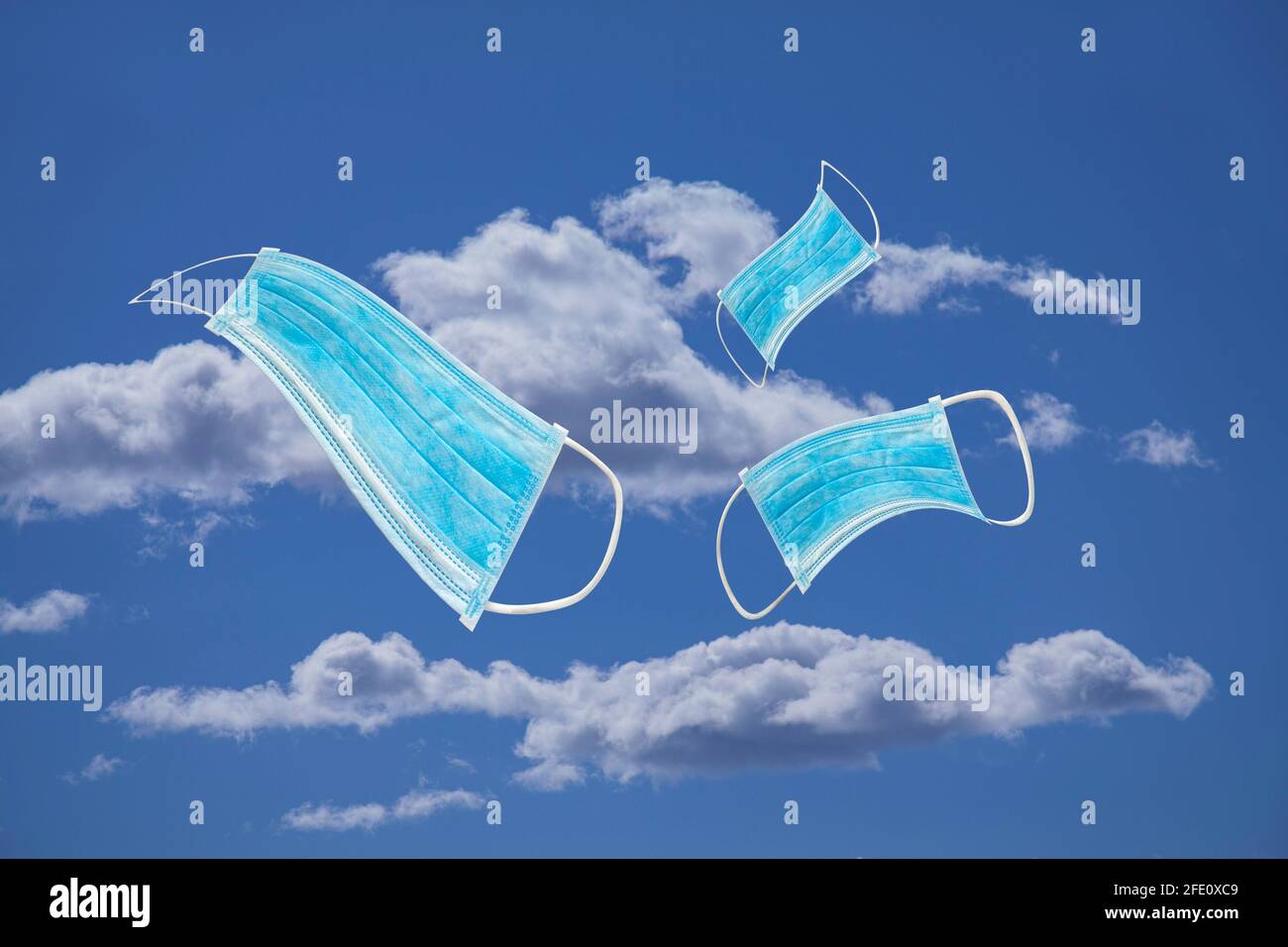 Maschera medica protettiva blu che vola in aria con cielo blu e nuvole bianche di fondo. Senza indossare la maschera o il concetto di inquinamento. Foto Stock
