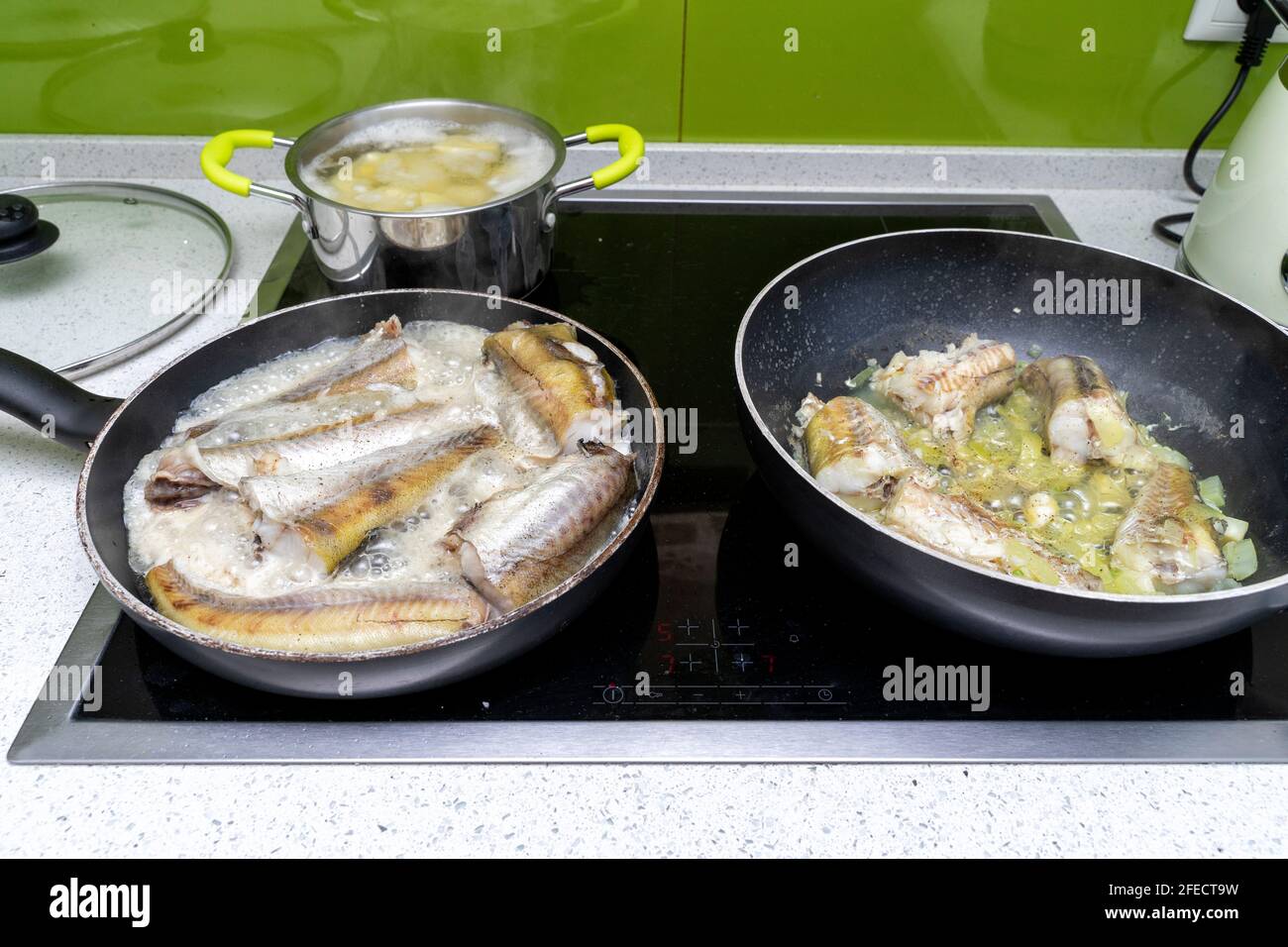 il pesce è cotto in due padelle su una stufa elettrica. Foto Stock