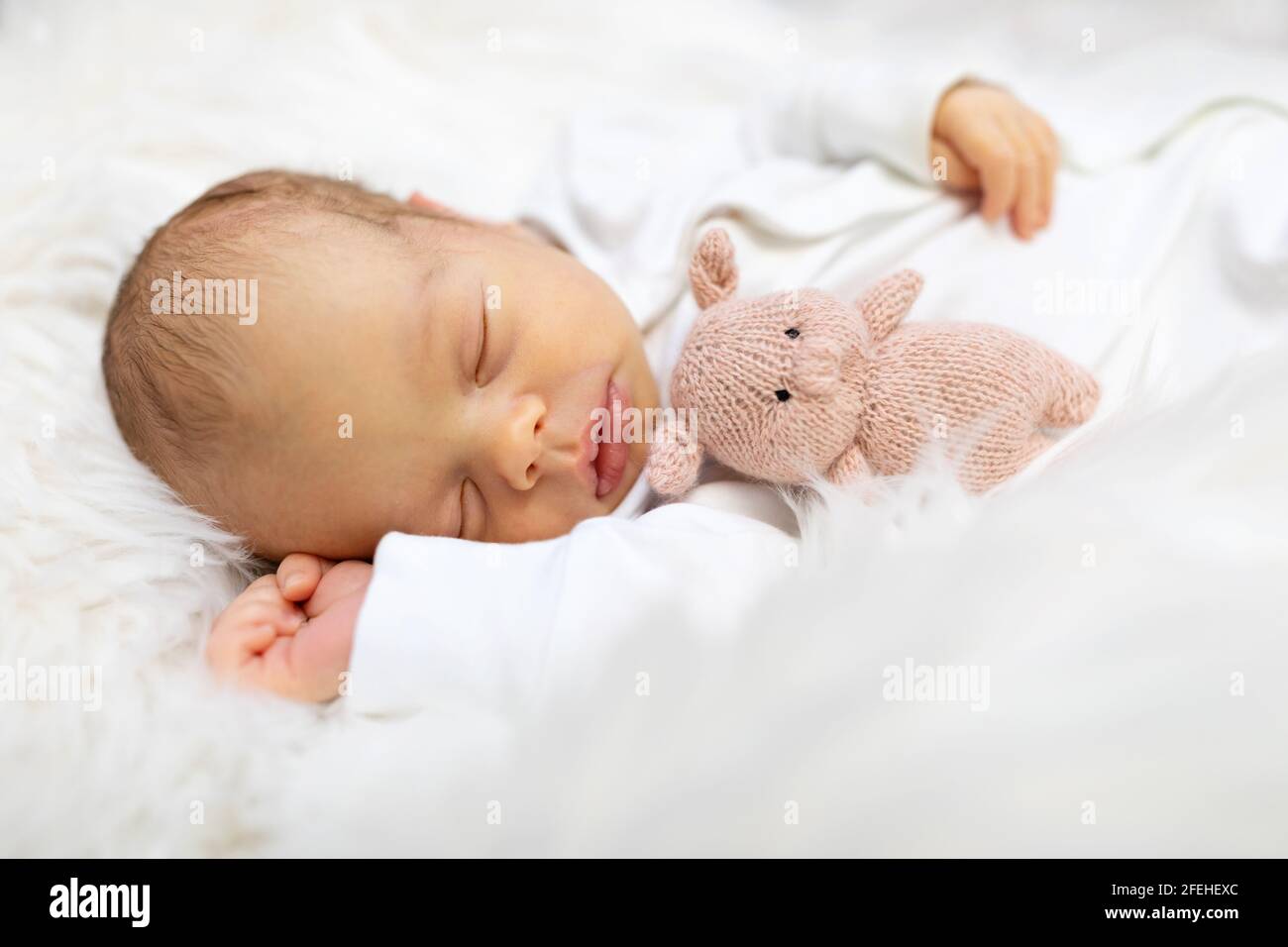 Adorabile neonato di una settimana in camera da letto bianca. Bambino neonato che si rilassa a letto. Asilo nido per bambini. Tessuto e biancheria da letto per bambini. Famiglia Foto Stock