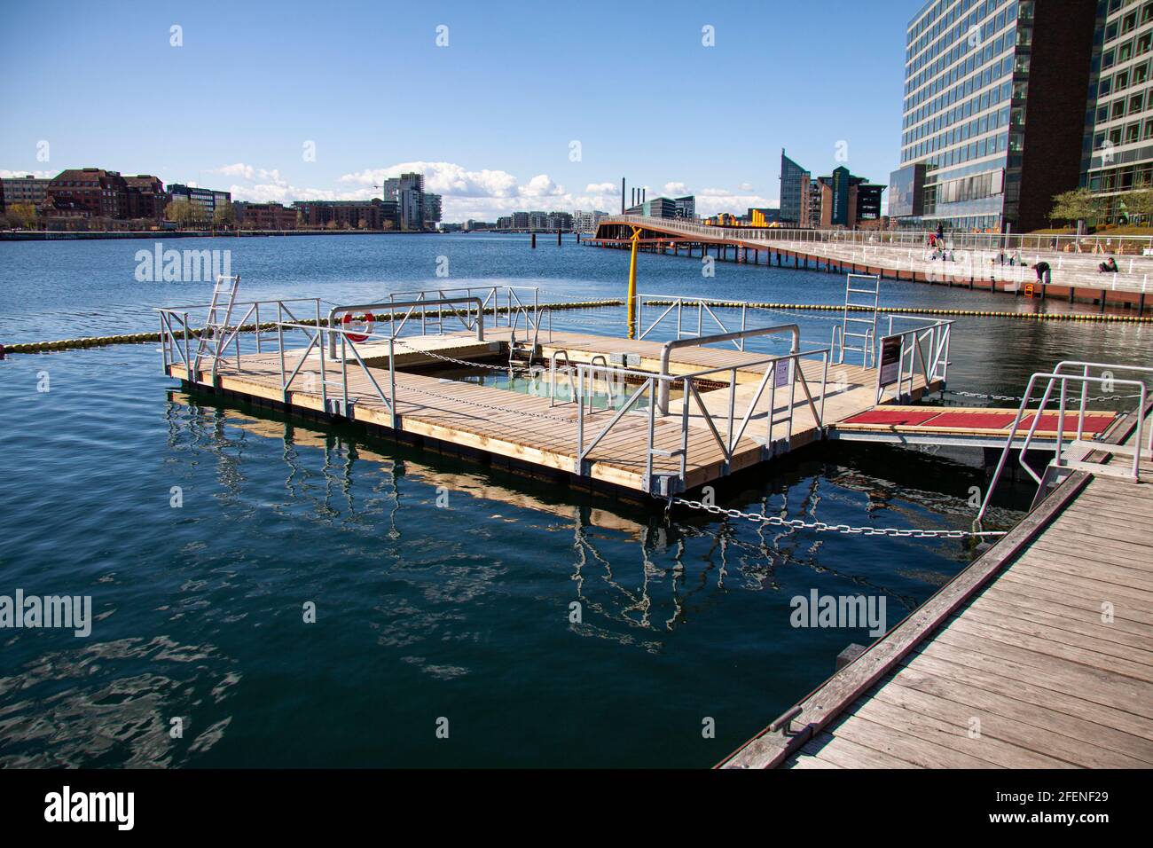 Zona di balneazione tutto l'anno vicino alla passerella in legno nella città urbana. Edifici e cielo blu sullo sfondo. Copenaghen, Danimarca - 23 aprile 2021. Foto Stock