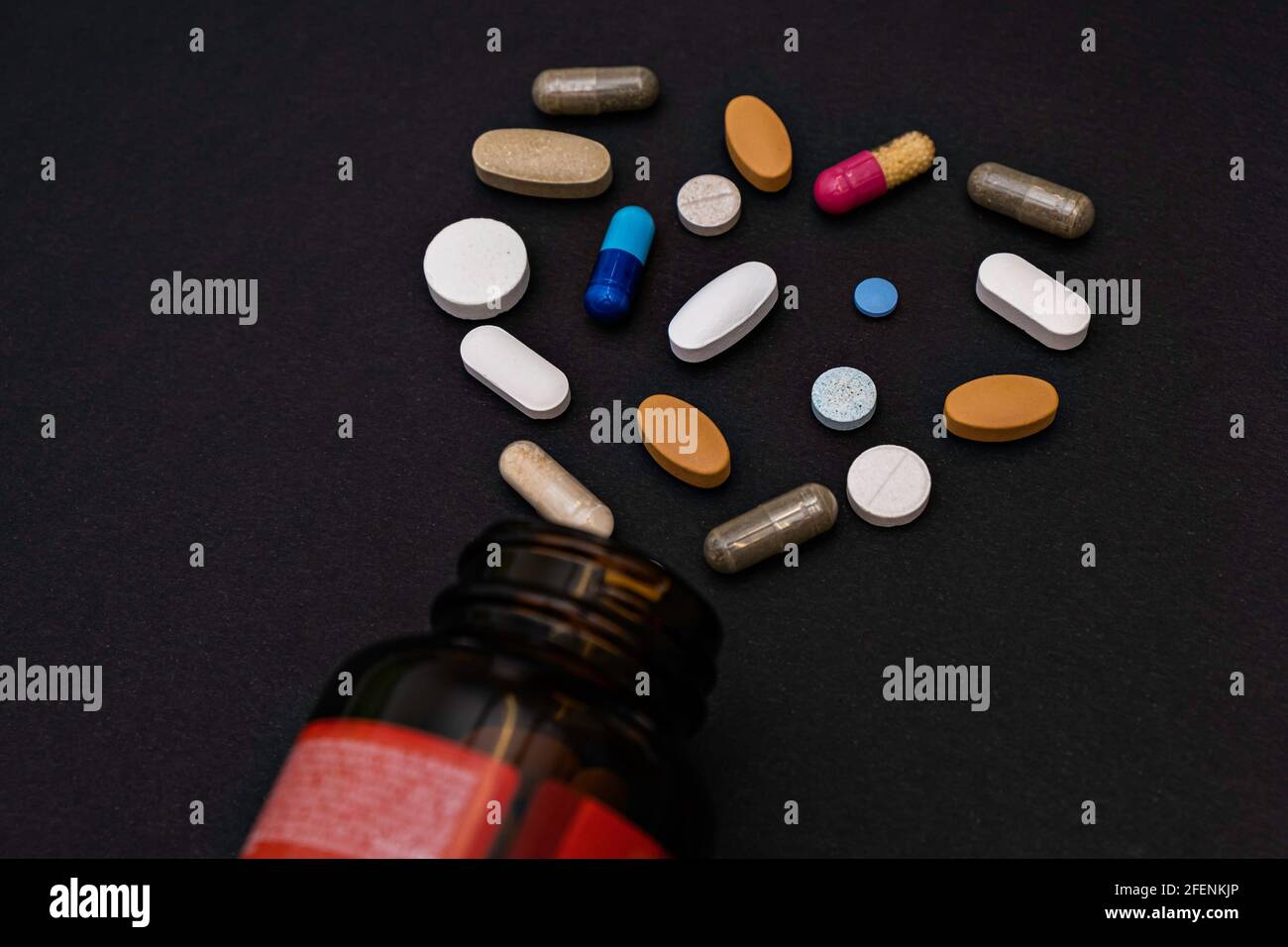 Primo piano colorful assortite capsule molli pillole vitamine a forma di cuore e vasetto integratori a base di fondo nero Foto Stock