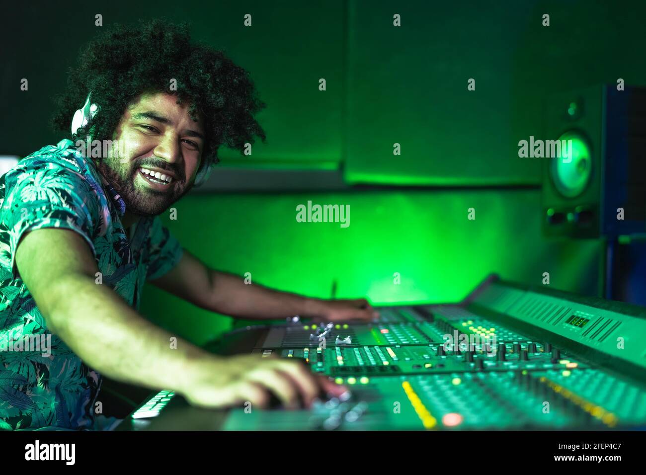 Giovane afro uomo che lavora in studio di registrazione musicale - Male ingegnere audio che mescola un suono in casa di produzione Foto Stock