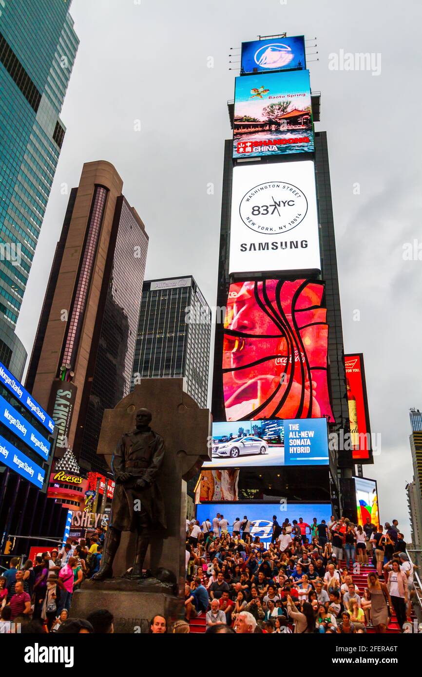 Persone che si siedono sui gradini rossi a Times Square in una serata impegnativa Foto Stock