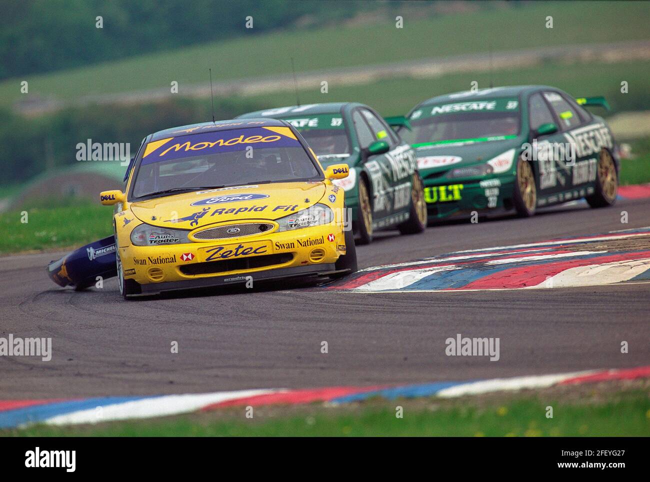 Alain Menu con il paraurti posteriore appeso al suo Ford Team Mondeo che viene cacciato giù da Jason Plato e Jean-Christophe Boullion nel loro Nescafe Blend 37 Williams Renault Laguna durante il campionato 1999 British Touring Car a Thruxton England. Foto Stock