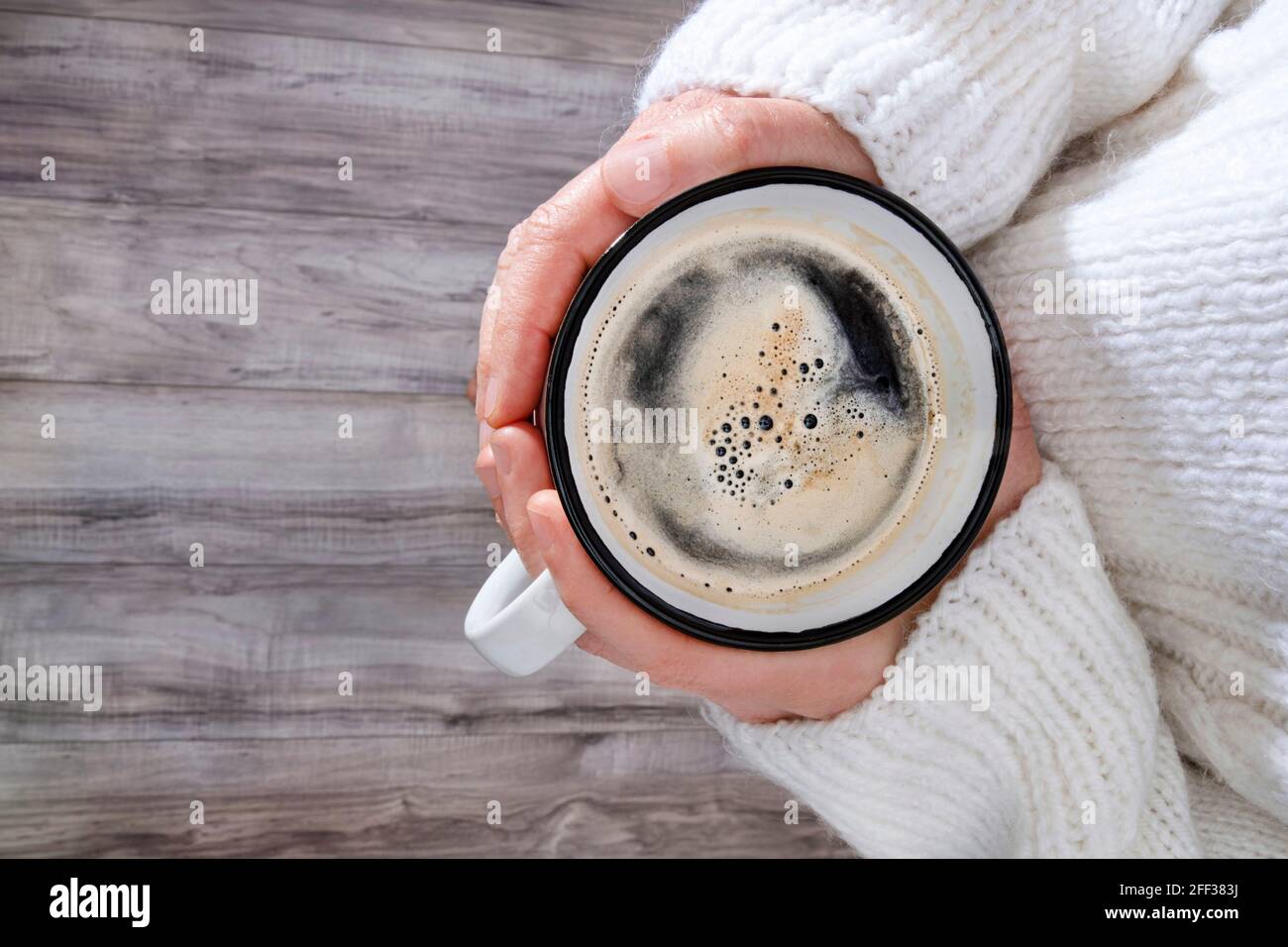 Una tazza di caffè confortevole nelle mani di una donna con un grande e accogliente ponticello Foto Stock