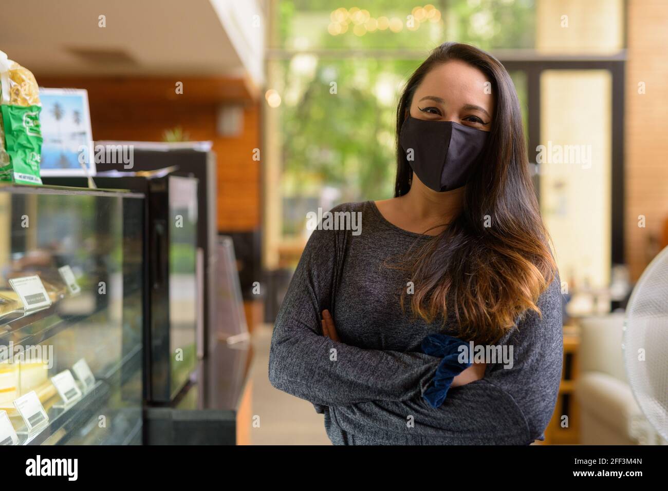 Ritratto di donna sicura indossando maschera facciale per la protezione contro Coronavirus Covid-19 al ristorante Foto Stock
