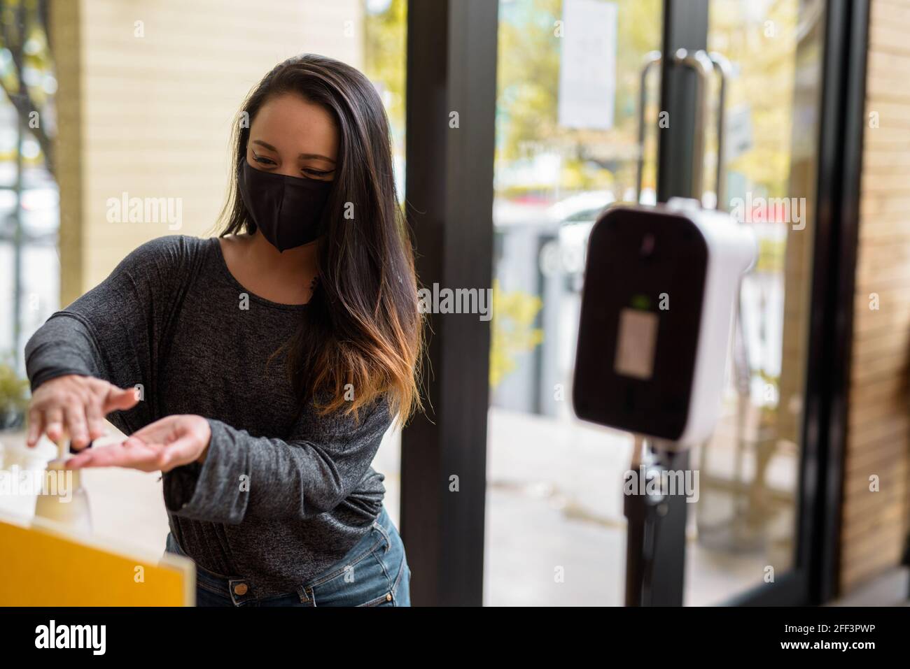 Donna che indossa la maschera per la protezione e lavarsi le mani con Gel alcolico contro il coronavirus Covid-19 Foto Stock