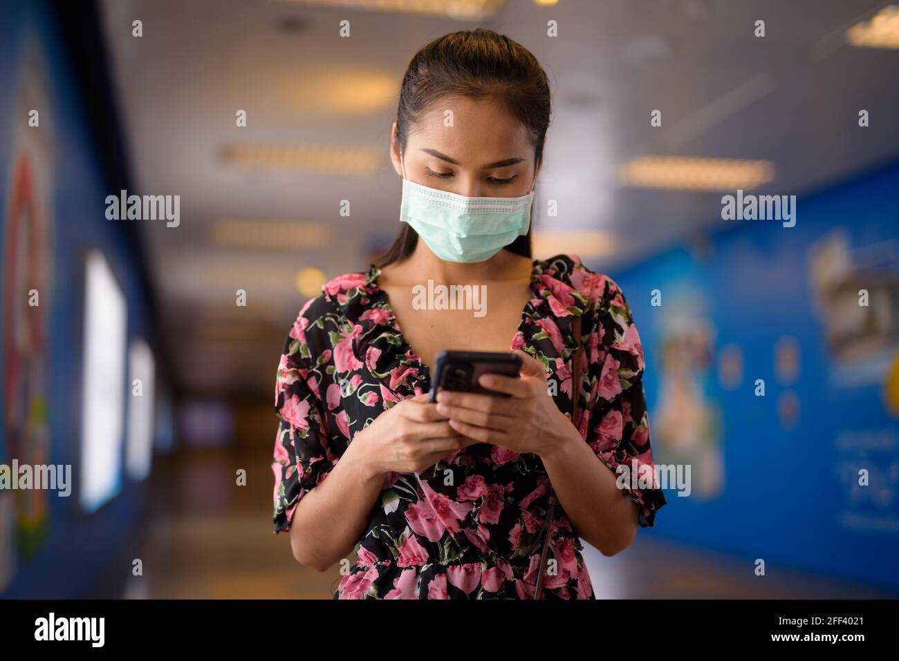 Ritratto di donna che indossa maschera per la protezione contro il coronavirus Covid-19 mentre si utilizza un telefono cellulare Foto Stock