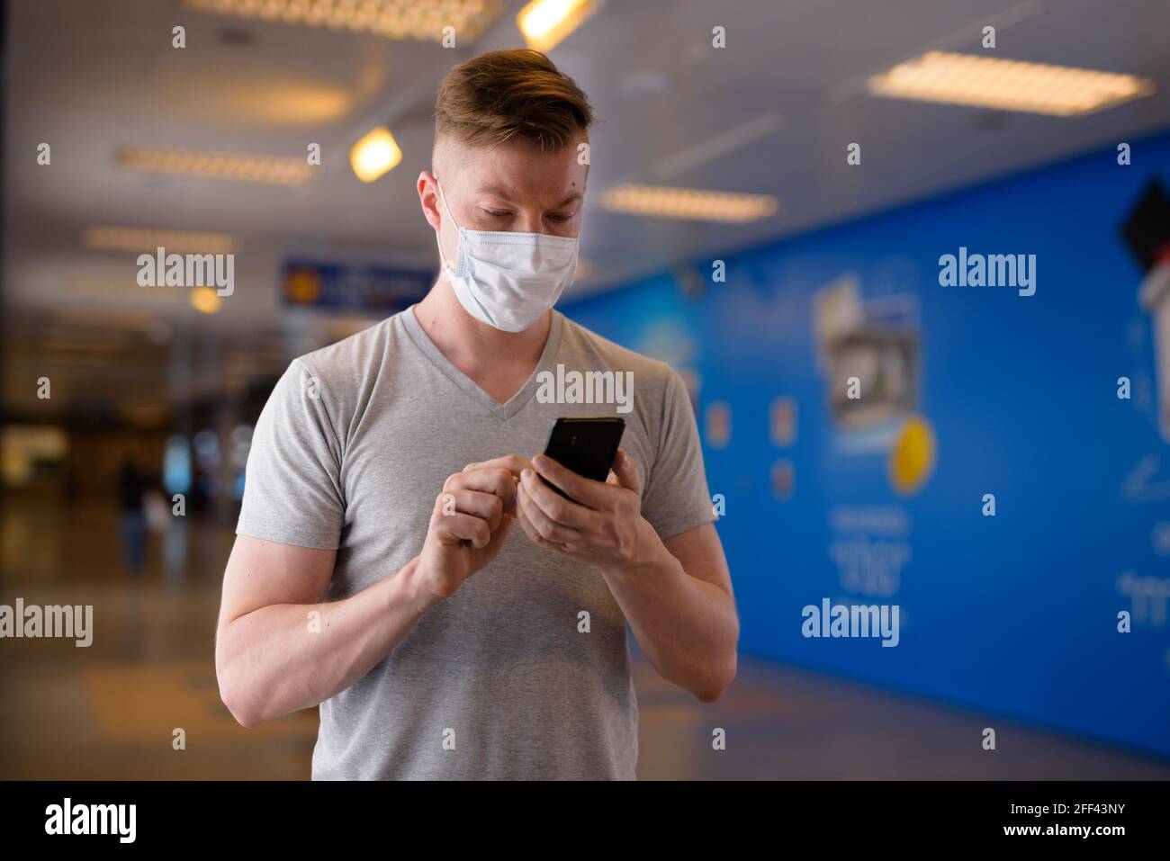 Uomo turistico che indossa maschera per la protezione contro il coronavirus Covid-19 mentre si utilizza un telefono cellulare Foto Stock