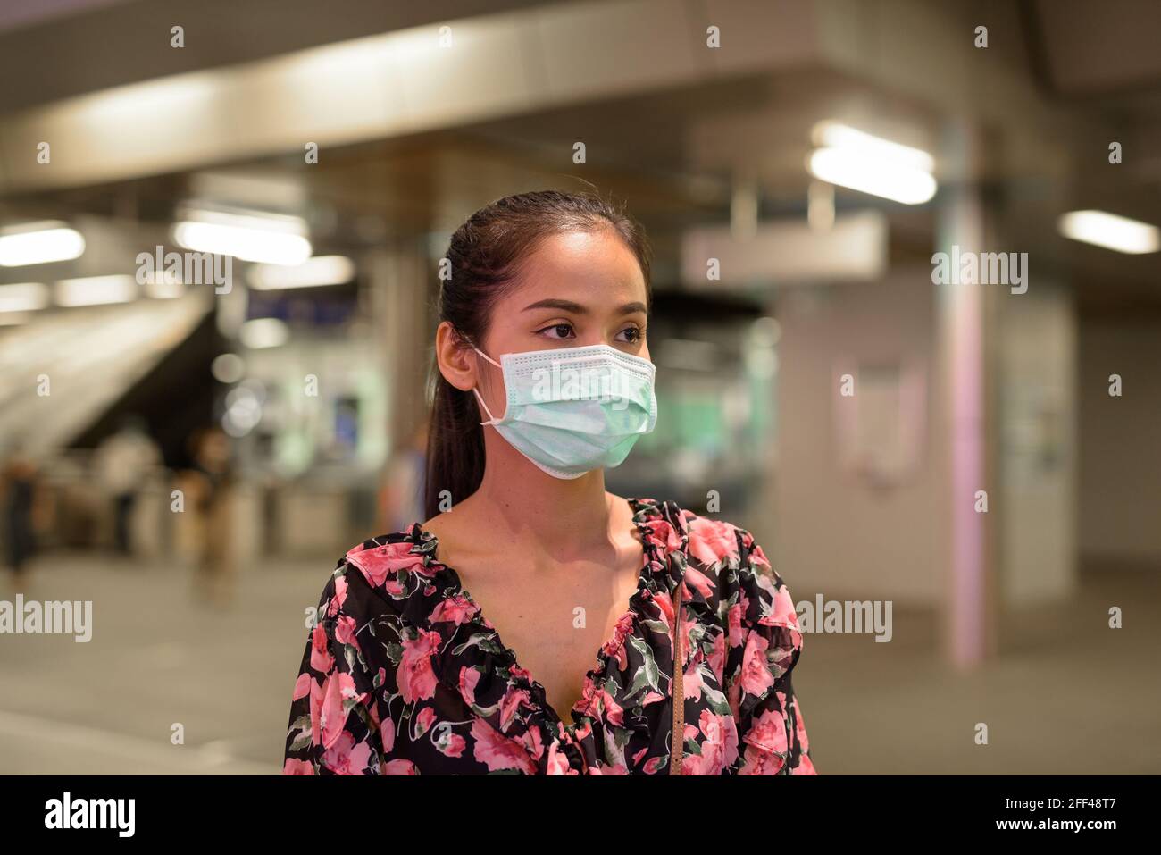 Donna che indossa maschera facciale per la protezione contro il coronavirus Covid-19 all'aperto di notte Foto Stock