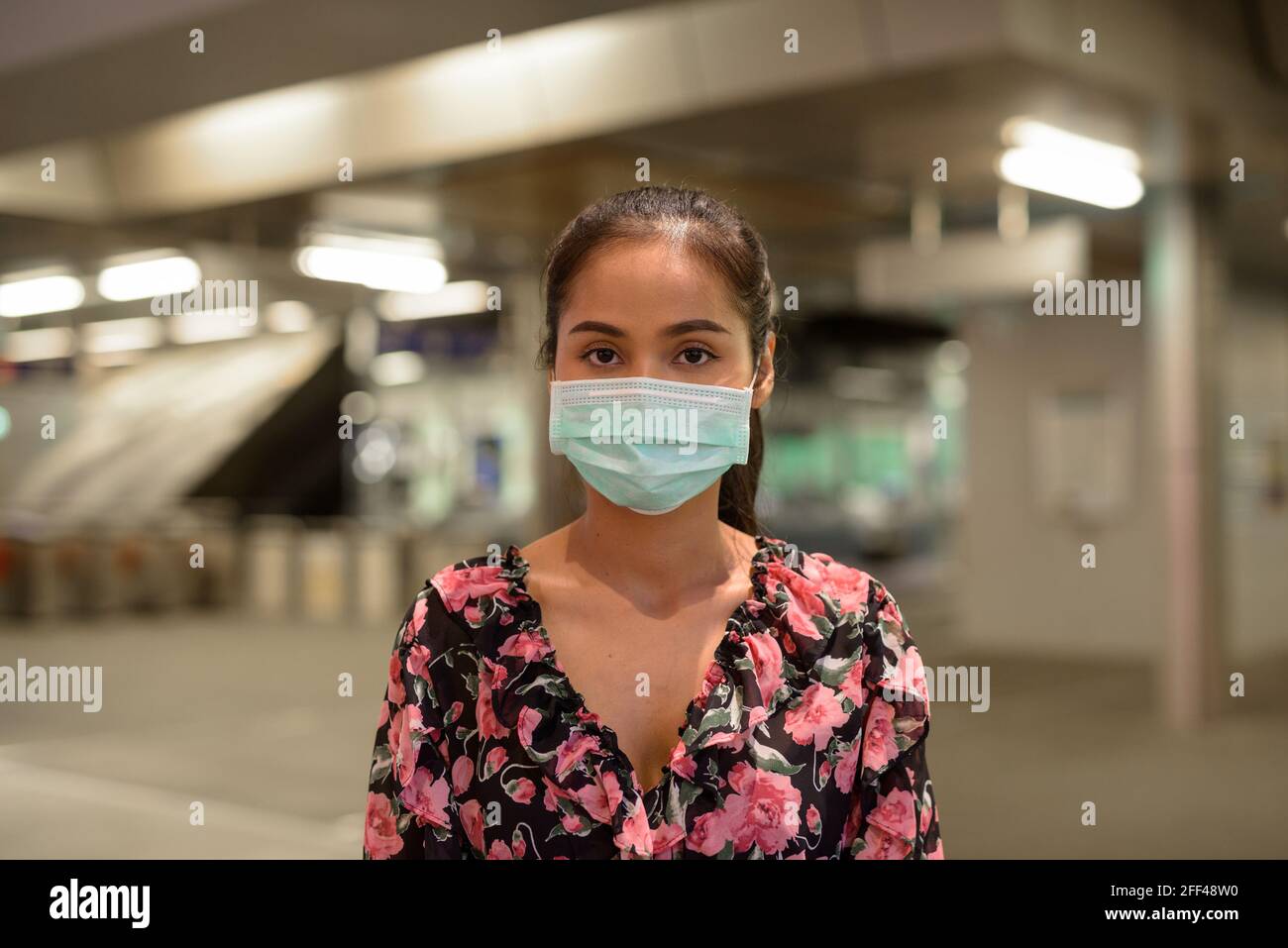 Donna che indossa maschera facciale per la protezione contro il coronavirus Covid-19 all'aperto di notte Foto Stock
