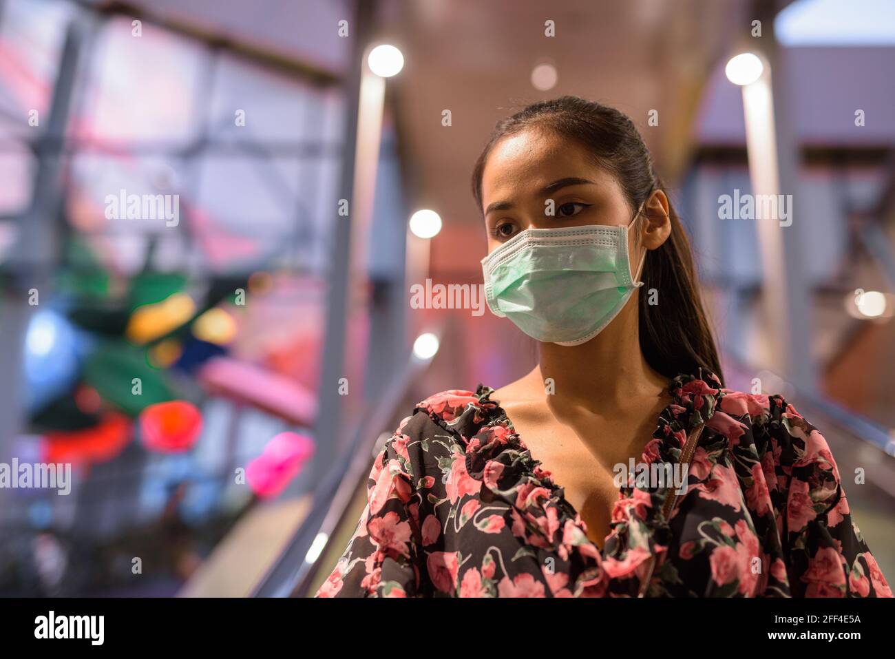 Ritratto di donna che indossa maschera per la protezione contro il coronavirus Covid-19 a scala mobile all'aperto Foto Stock