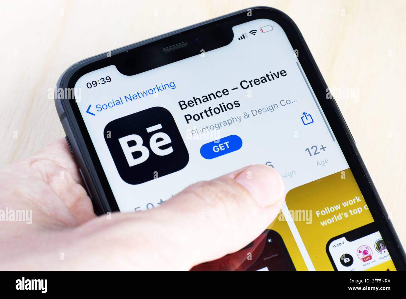 Donna che scarica l'app Behance su AppStore. Behance è una piattaforma di social media di proprietà di Adobe "per mostrare e scoprire il lavoro creativo" Foto Stock