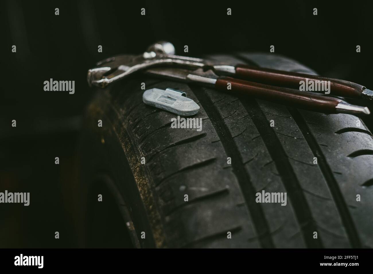 Primo piano di una chiave e di un peso di equilibratura del ferro su un  pneumatico per auto in officina Foto stock - Alamy