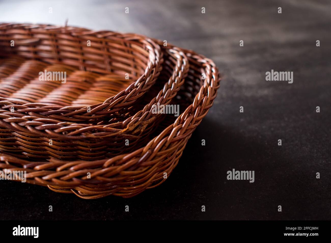 Alcuni cestini marroni fatti a mano su un tavolo di legno nero Foto Stock