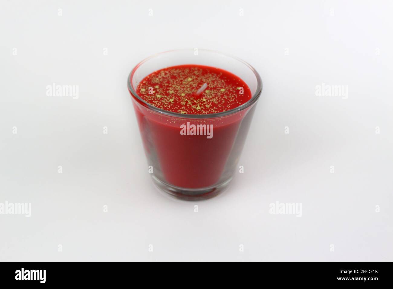 Candela profumata rossa con stelle dorate isolate su sfondo bianco Foto Stock