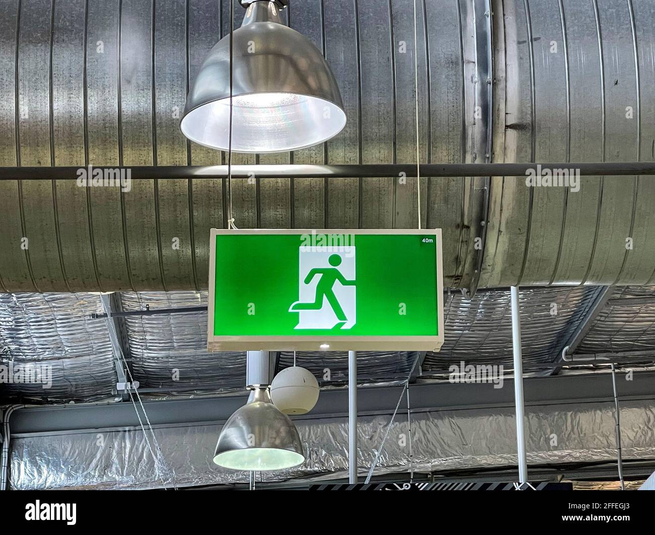 Negozio classico Fire Exit e Emergency Escape nel area pubblica di un centro commerciale raffigurante una corsa uomo e una freccia che indica le direzioni Foto Stock