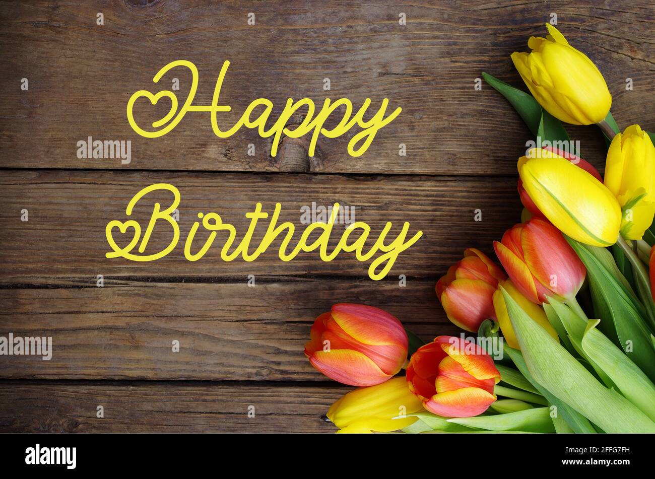 Happy Birthday testo con tulipani fresco colorato su legno vintage rustico sfondo. Tulipani su tavola di legno con testo Happy Birthday.Greeting card. Foto Stock