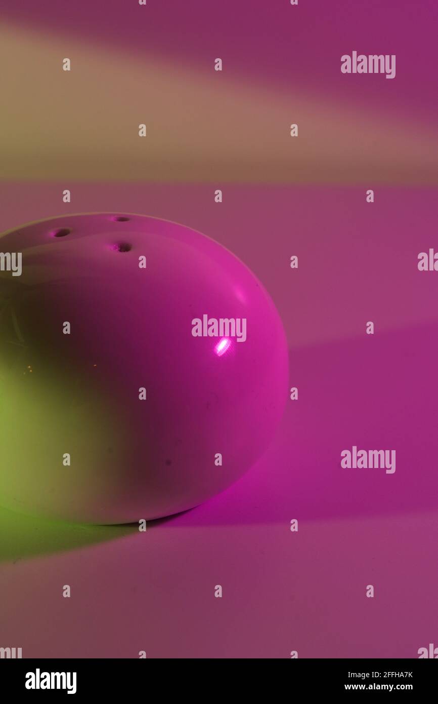 Studio astratto di un agitatore bianco sotto una vivace illuminazione verde neon e magenta. Elevato contrasto di colore e riflesso Foto Stock