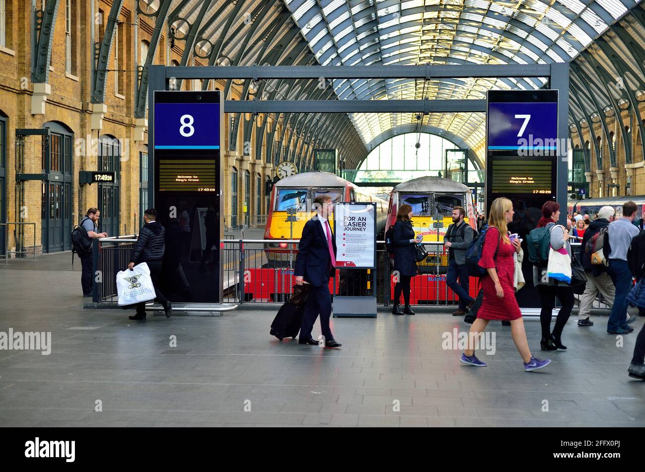 Londra, Inghilterra, Regno Unito. I passeggeri passano i binari presso il London King's Cross, un importante terminal ferroviario sul confine settentrionale del centro di Londra. Foto Stock