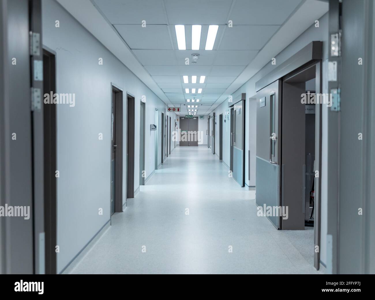 Corridoio bianco vuoto e pulito in un moderno ospedale con illuminazione a soffitto, foderato di porte Foto Stock