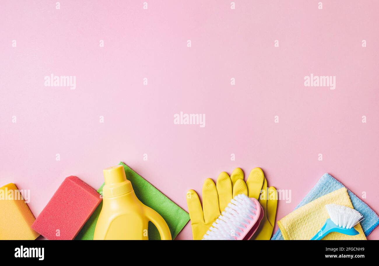 Prodotto per la pulizia della casa su sfondo rosa, spazio per la copia. Disposizione piatta o vista dall'alto. Servizio di pulizia o di pulizia con spazio per testo o design Foto Stock