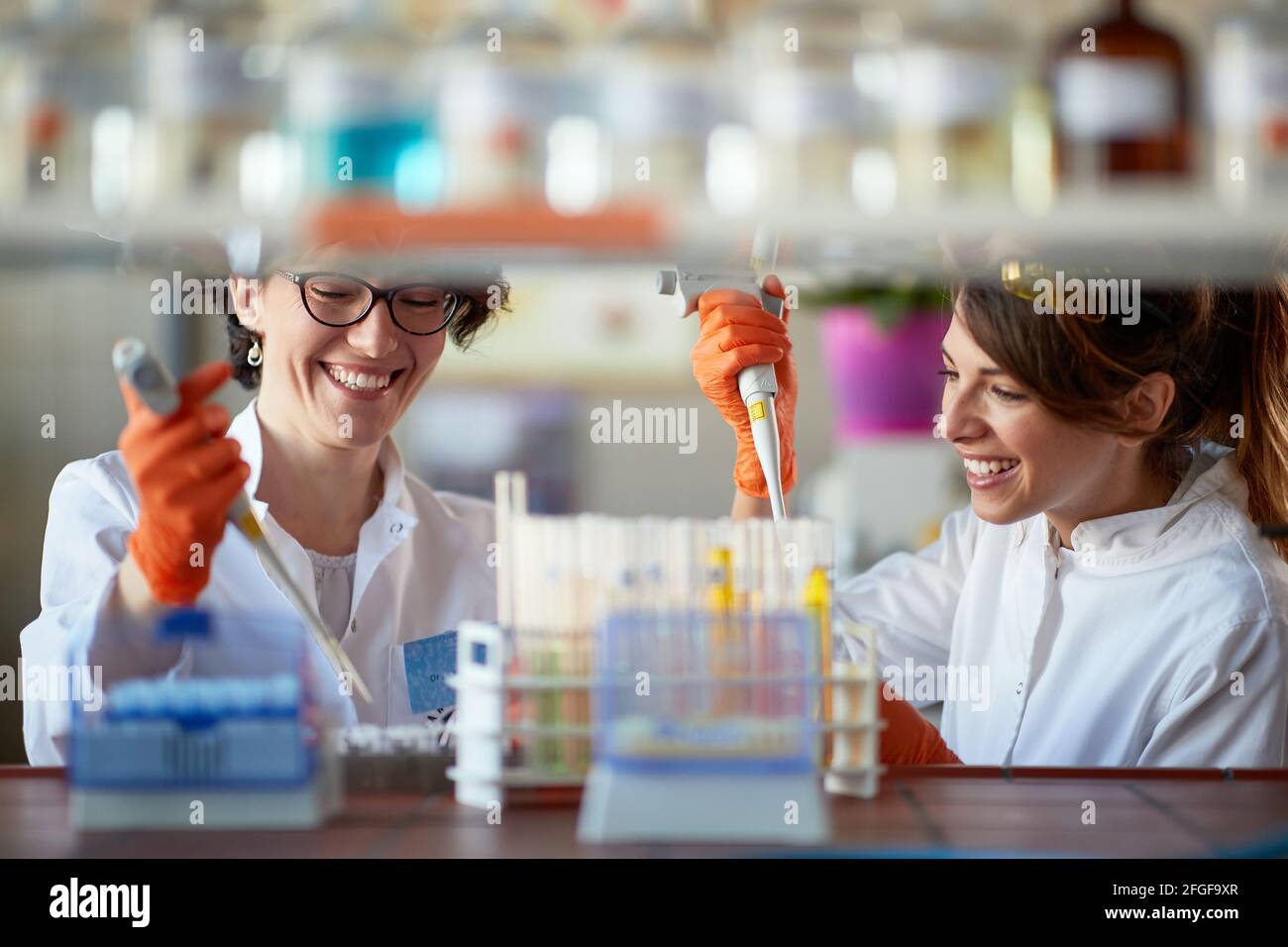 Una giovane studentesse si divertisce durante il pipettaggio in un ambiente di laboratorio sterile. Scienza, chimica, laboratorio, persone Foto Stock
