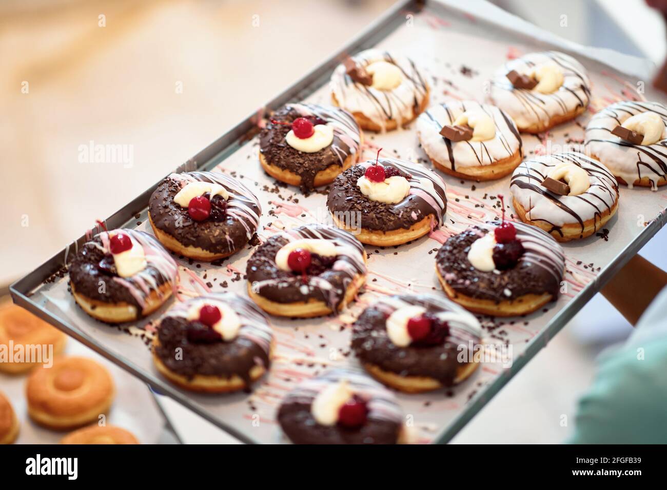 Un vassoio pieno di deliziose ciambelle fatte a mano dall'aspetto irresistibile pronto per una pasticceria. Pasticceria, dessert, dolce, fare Foto Stock
