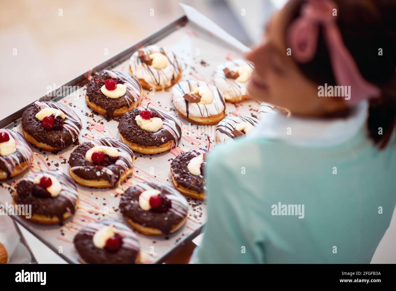 Una giovane piccola impresa donna proprietario è soddisfatto circa di ciambelle deliziose fatte a mano di irresistibilità aspetto pronto per una pasticceria. Pasticceria, des Foto Stock