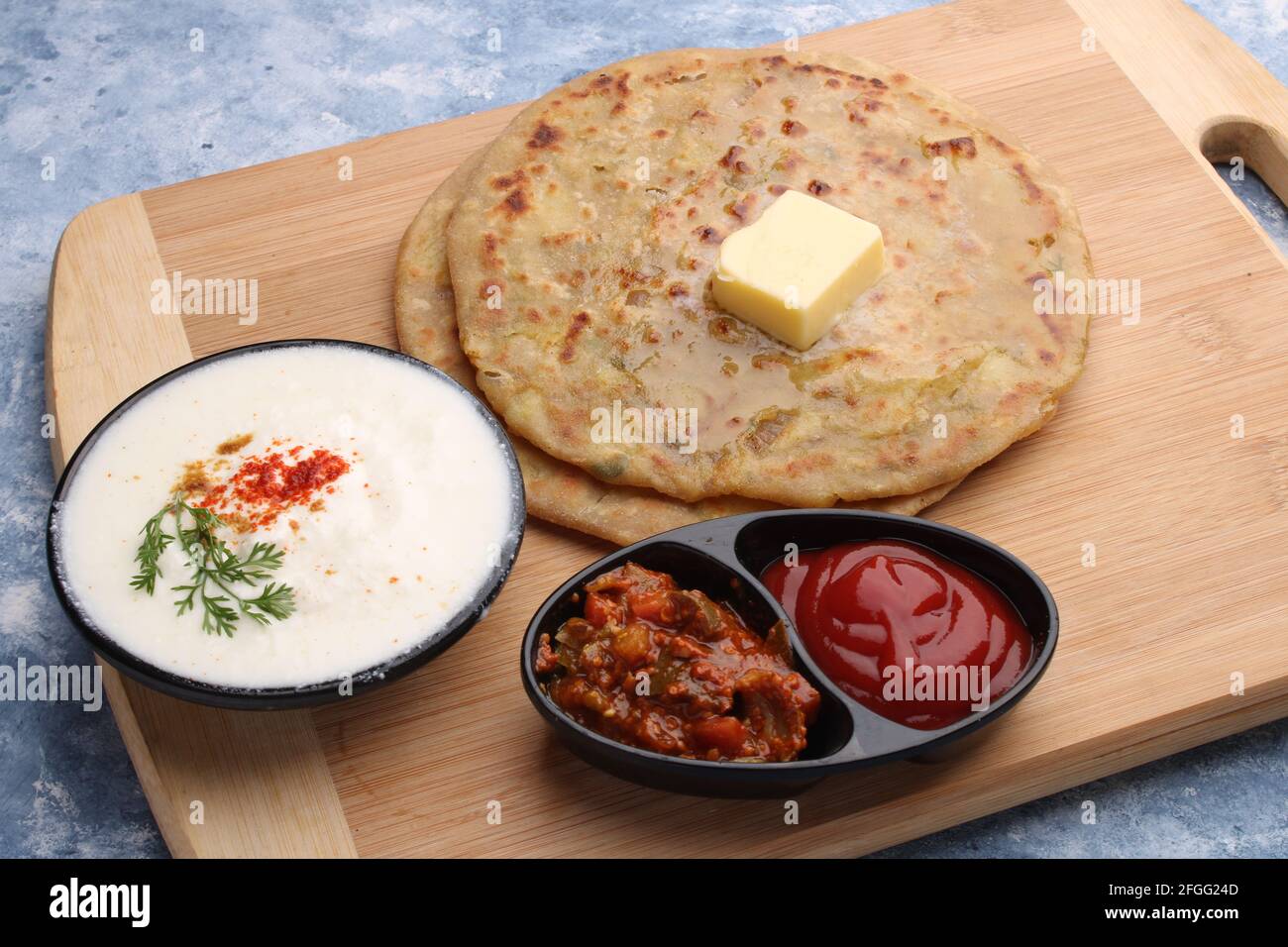 Piatti indiani tradizionali Aloo paratha o patate farcito pane piatto. Servito con sottaceti di pomodoro ketchup e cagliato, burro, cipolla chili. Foto Stock