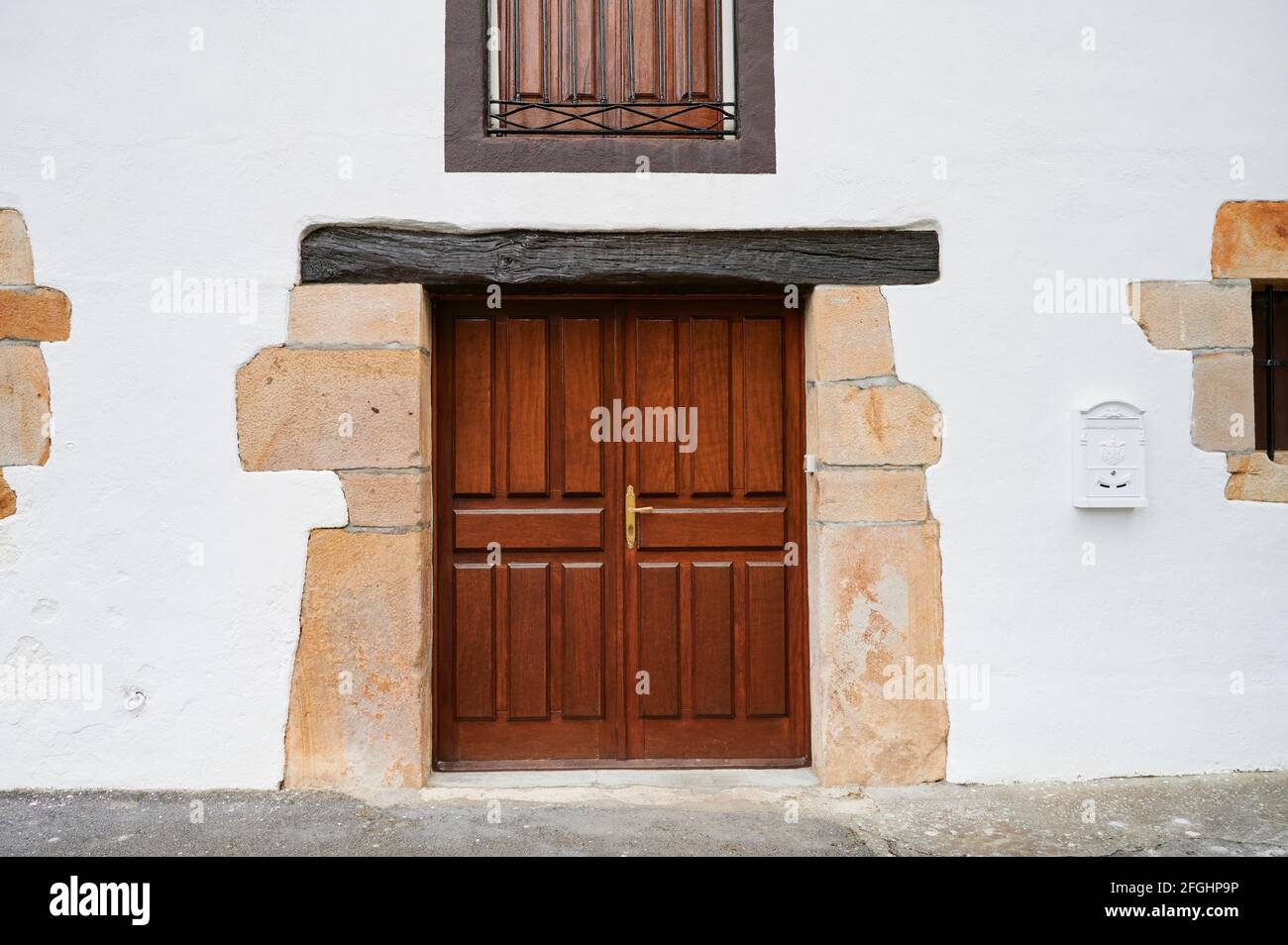 Facciata bianca con porta in legno e cassetta postale bianca Foto Stock