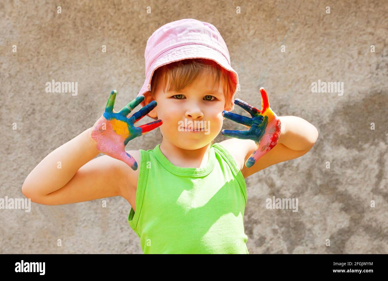 Felice giovane bambina di età scolastica, ragazza che tiene su entrambe le mani coperte in vernice colorata, ritratto all'aperto, stile di vita sparato Bambini e arte, cre Foto Stock