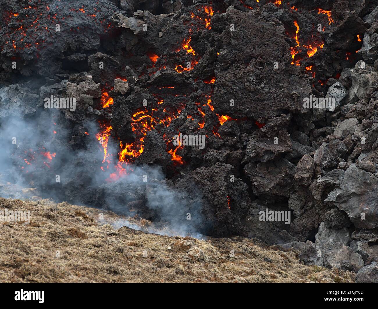 Vista ravvicinata delle rocce laviche incandescenti che si raffreddano dopo l'eruzione vulcanica nella valle di Geldingadalir vicino al monte Fagradalsfjall, Grindavík, Islanda. Foto Stock