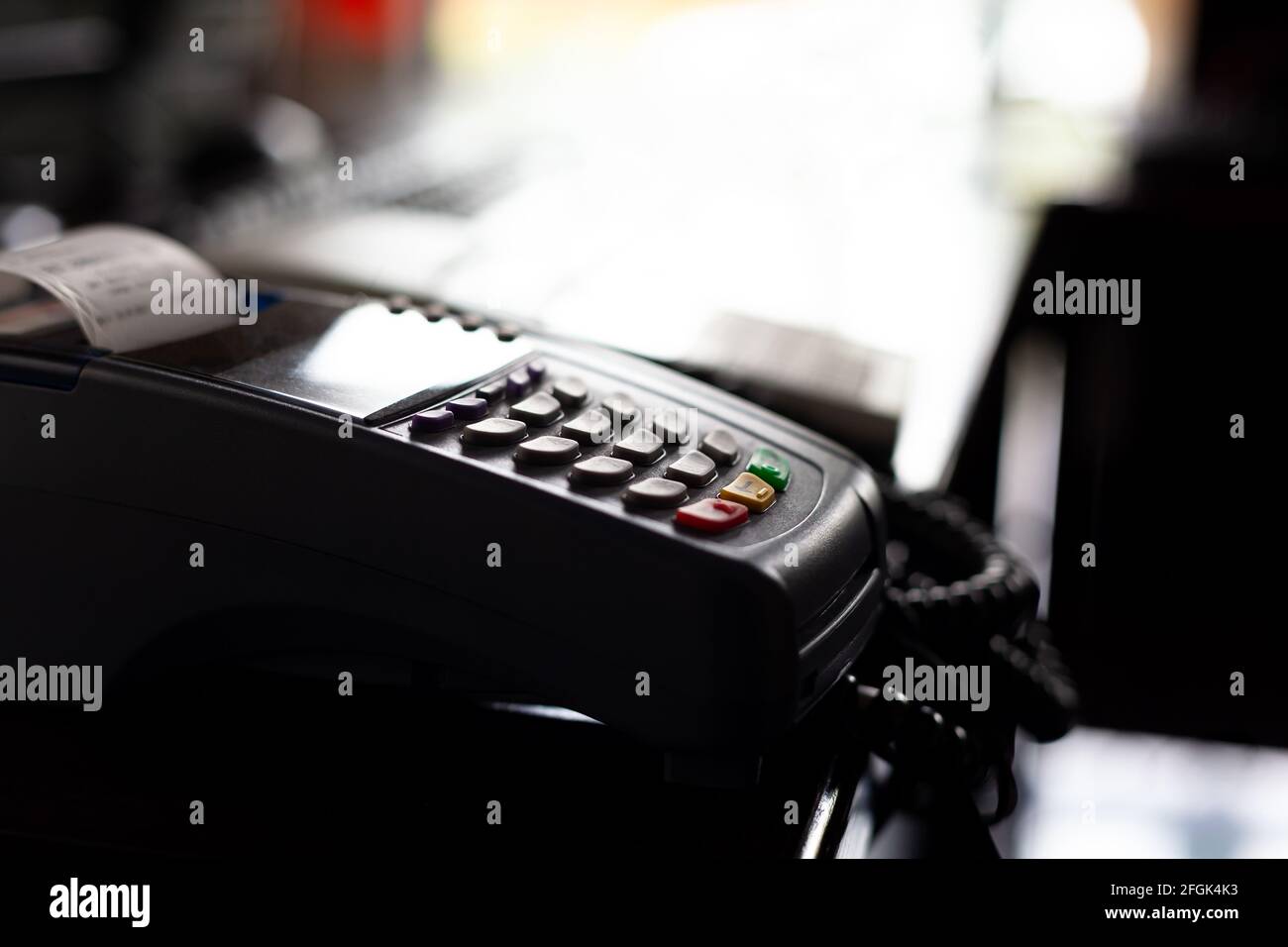 Terminale di pagamento della carta POS nel negozio oscurato, dettaglio dell'oggetto, primo piano, dof poco profondo, vista laterale. Terminale di pagamento senza contanti all'interno di un oscuro chiuso sto Foto Stock