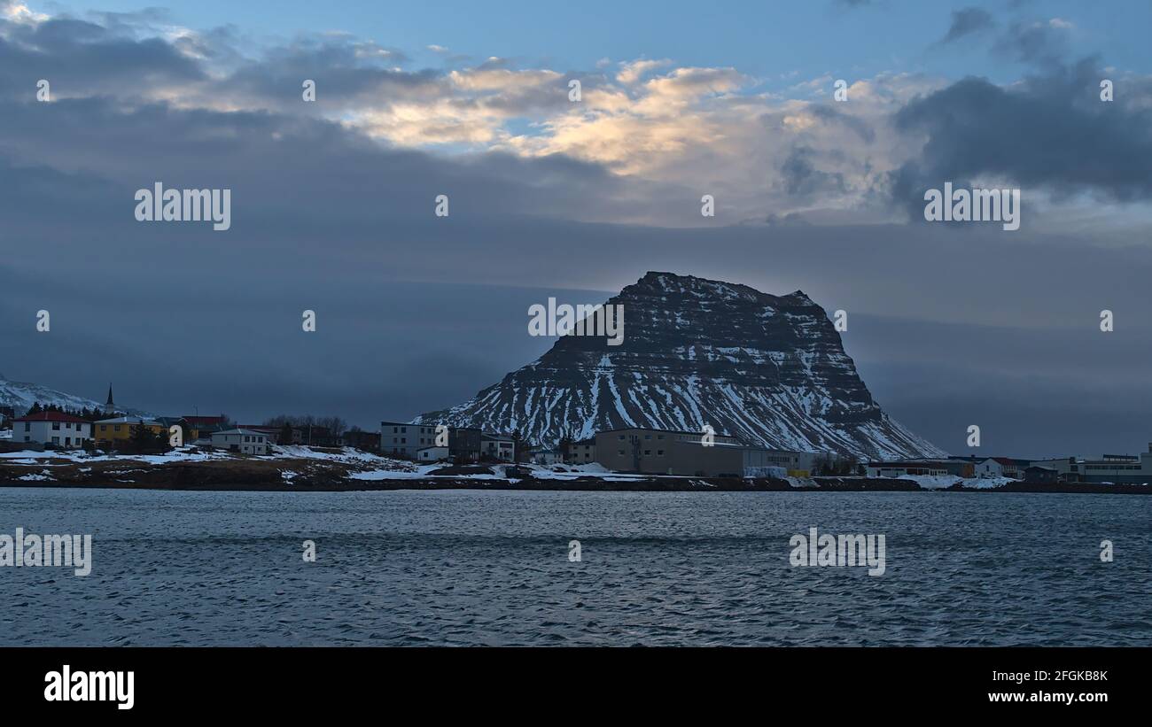 Vista del piccolo villaggio Grundarfjörður sulla costa atlantica settentrionale della penisola di Snæfellsnes, Islanda con la chiesa e gli edifici con la montagna. Foto Stock