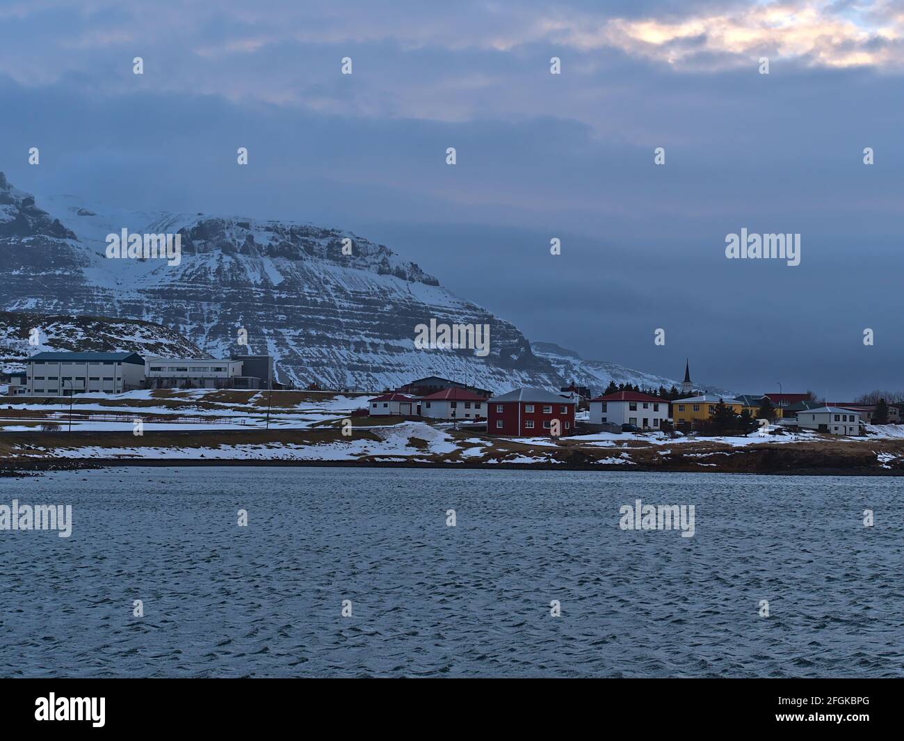 Vista del piccolo villaggio Grundarfjörður sulla costa atlantica settentrionale della penisola di Snæfellsnes, Islanda con la chiesa e gli edifici di fronte montagna. Foto Stock