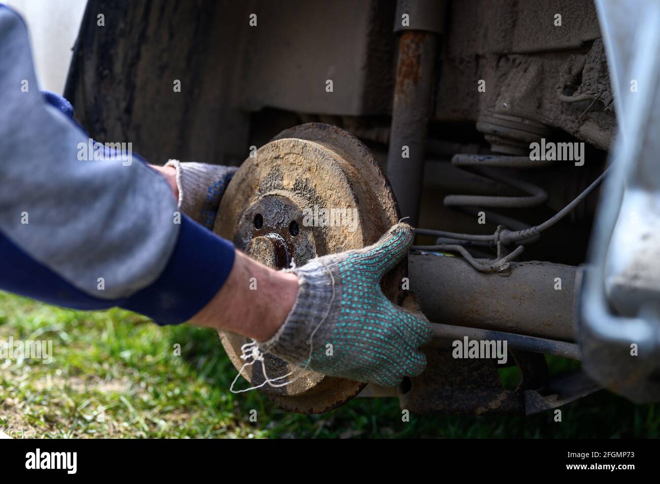 riparazione mani guanto uomo del freno a tamburo auto stesso. riparazione di freno a tamburo auto rotto smontato all'esterno Foto Stock